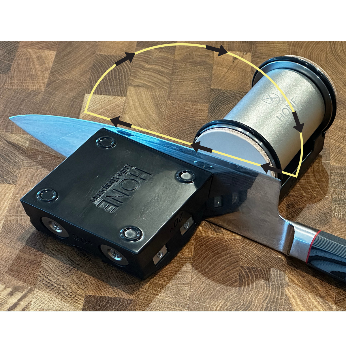 Knife in a HONE Knife Holder beside the Vertical Strop, with arrows showing a heel-to-tip stropping motion